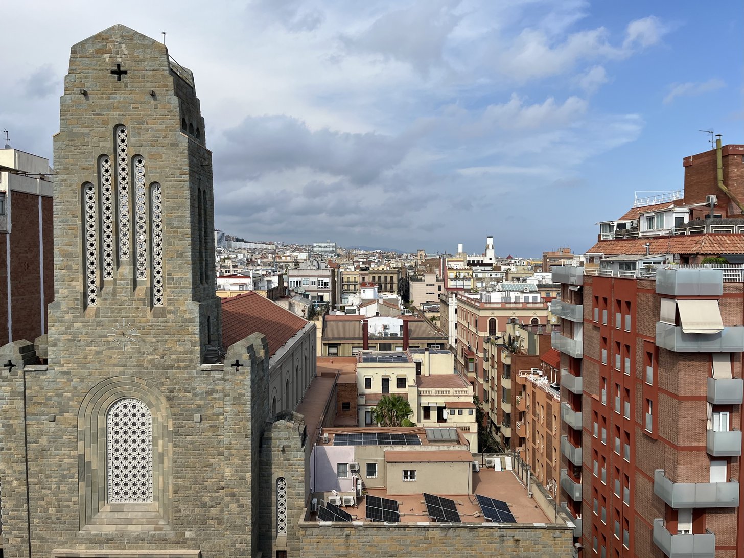 Uma torre de igreja sobre os telhados de Barcelona, com painéis solares.