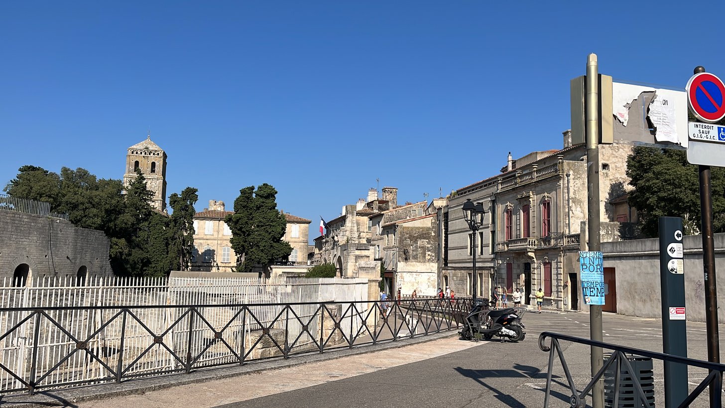 Uma rua de Arles, com as ruínas do teatro romano e uma torre românica ao fundo.