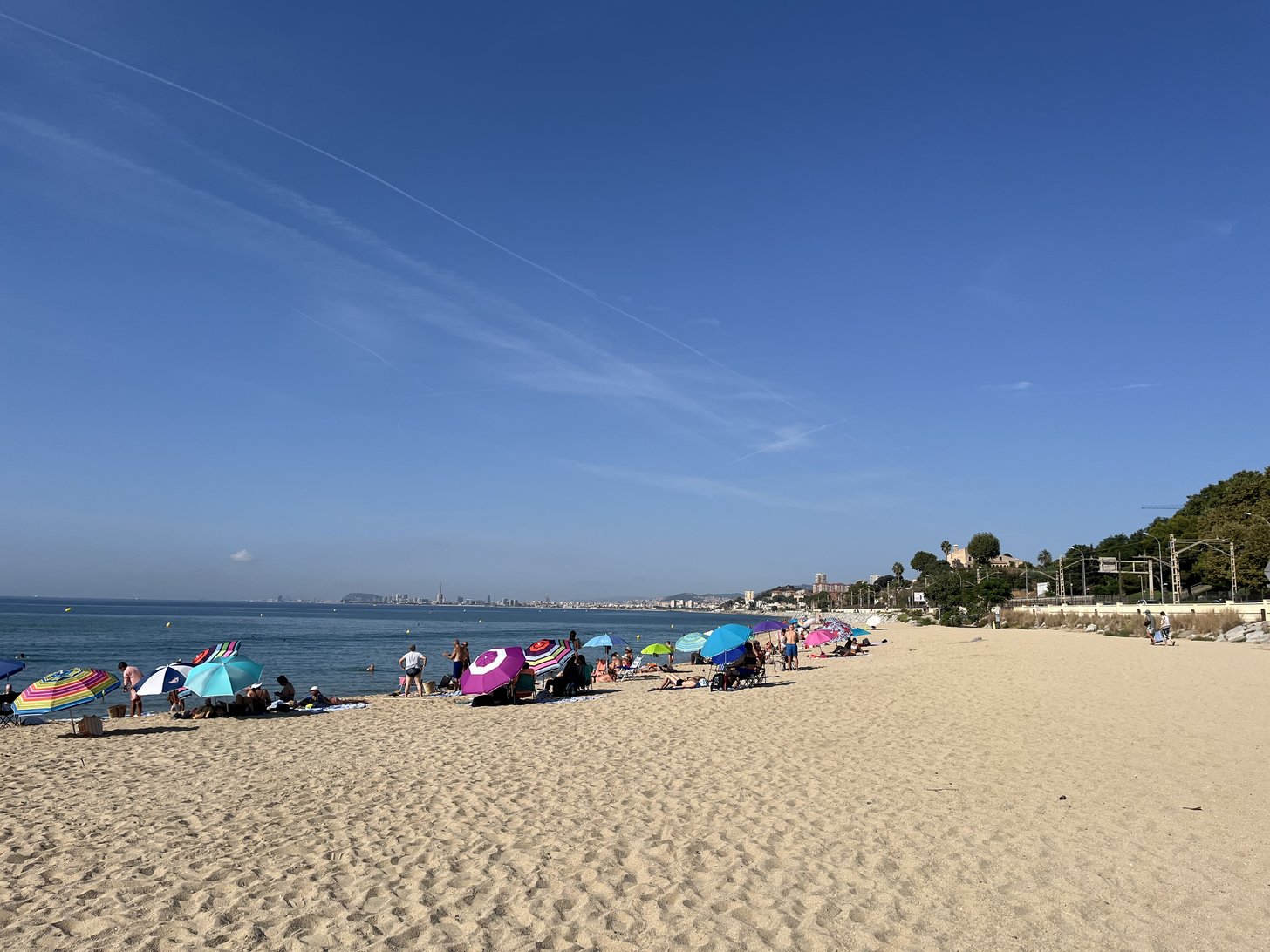 Uma praia com chapéus-de-sol, a cidade recortada ao longe.