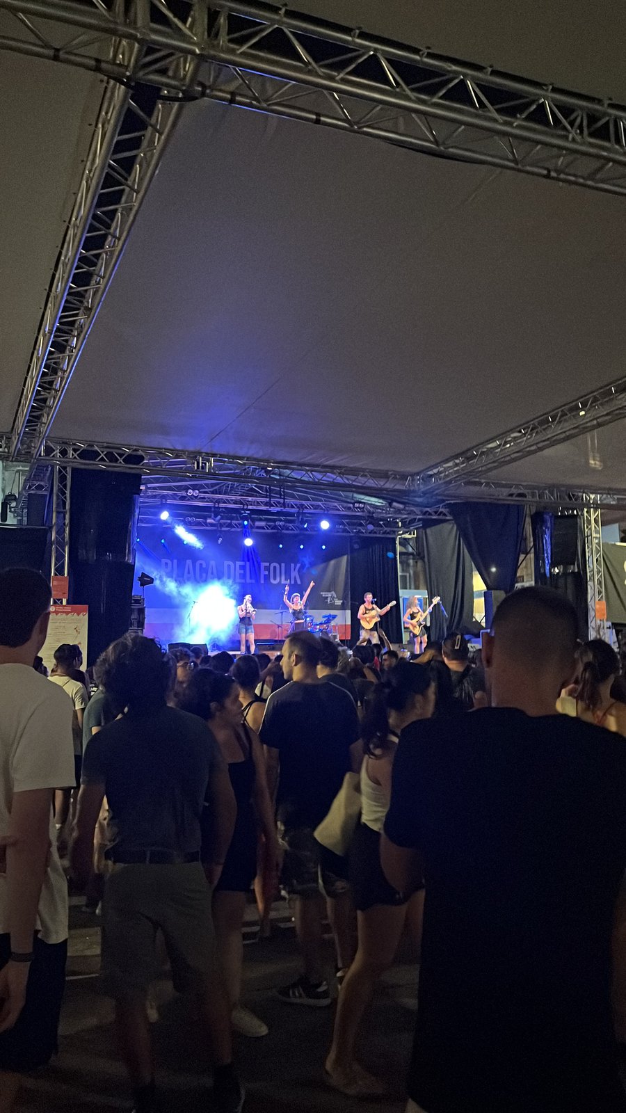 O palco da Plaça del Folk à noite, com o público de costas.