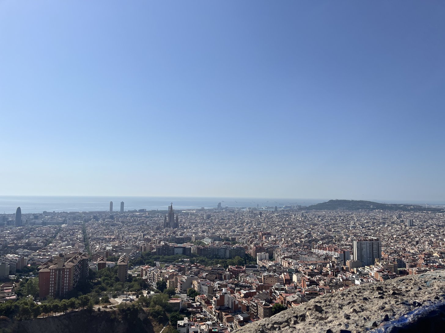 Barcelona vista dos montes, com a Sagrada Família e o mar ao fundo.