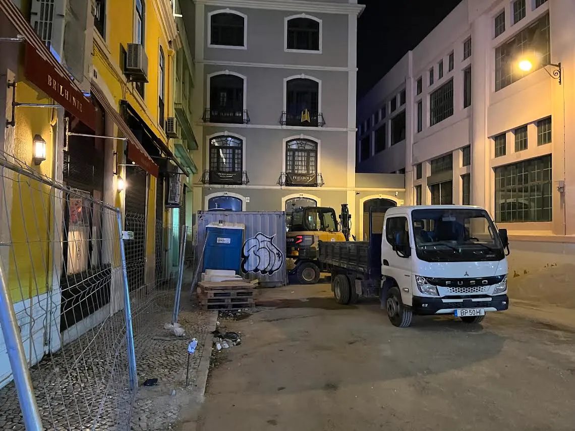 Rua nocturna com obras e um camião estacionado.