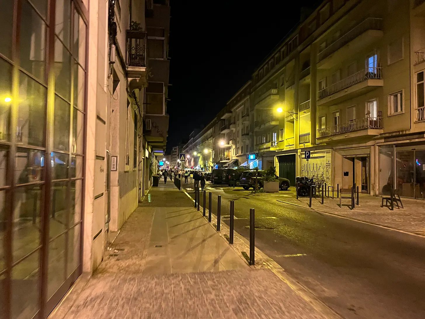 Rua deserta à noite, com os prédios iluminados a amarelo.