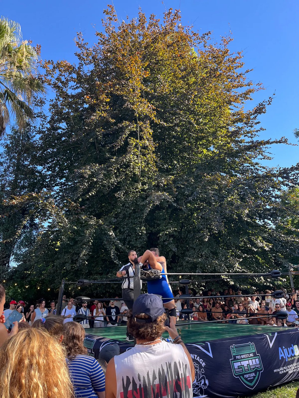 O ringue ao ar livre sob as árvores, com o público à volta das cordas.