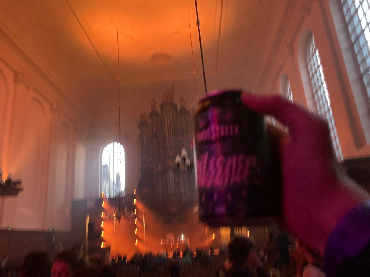 O órgão da igreja em luz laranja, uma lata erguida em primeiro plano.